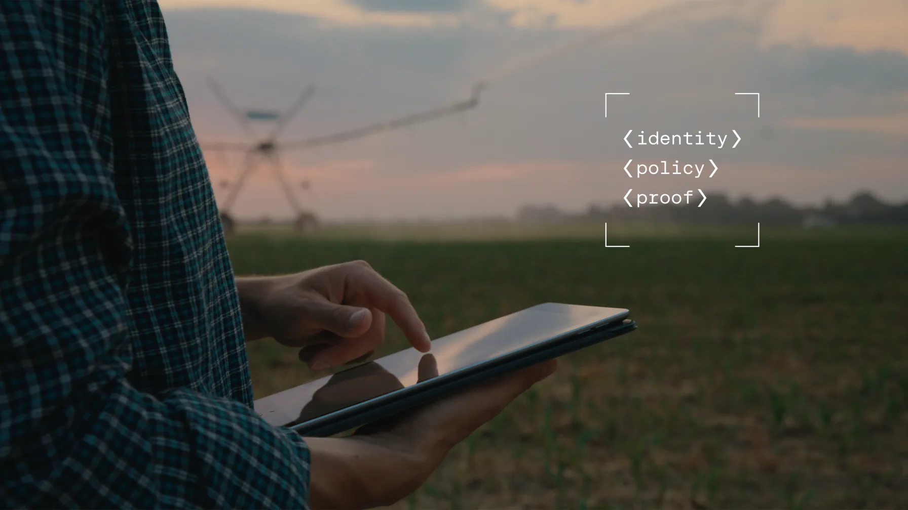 A worker using a tablet in a field at dusk beside an irrigation system
